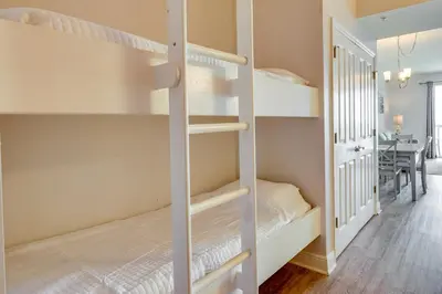 a bedroom with two bunk beds and a dining room at Balcony and Beach Access Oceanfront PCB Condo in Panama City Beach