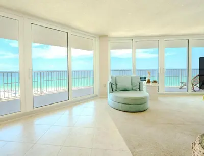 a living room with a chair and large windows at Dunes of Panama Resort in Panama City Beach