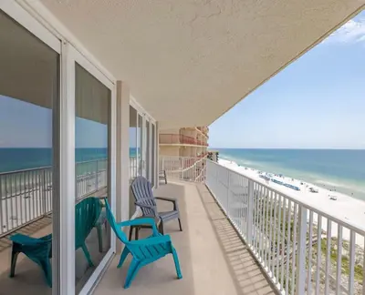 a balcony with two chairs and a view of the beach at Dunes of Panama Resort in Panama City Beach