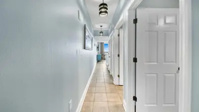 a hallway with white doors and a tile floor at Beachfront Condo #1413 Majestic Beach Resort in Panama City Beach