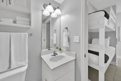 a white bathroom with a sink and a mirror at Beachfront Condo #608 at Majestic Beach Resort in Panama City Beach