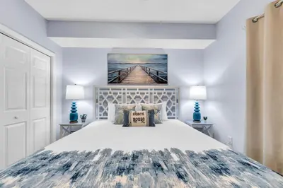 a bedroom with a large bed and a painting on the wall at Beachfront Condo #906 at Majestic in Panama City Beach
