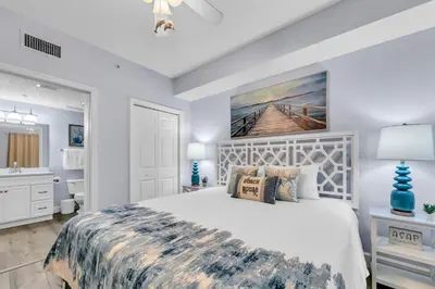 a bedroom with a large bed and a bathroom at Beachfront Condo #906 at Majestic in Panama City Beach