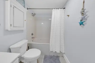 a white bathroom with a toilet and a shower at Beachfront Studio #1112 at Majestic in Panama City Beach