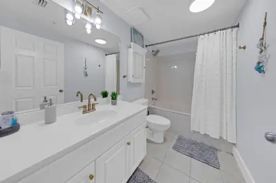 a white bathroom with a sink and a toilet at Beachfront Studio #1112 at Majestic in Panama City Beach