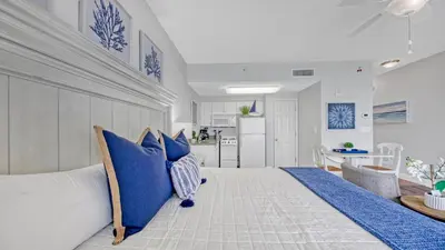 a bedroom with blue pillows on a white couch at Beachfront Studio #212 at Majestic in Panama City Beach