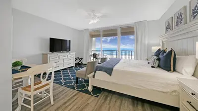 a bedroom with a bed and a desk and a television at Beachfront Studio #212 at Majestic in Panama City Beach