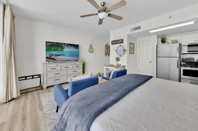 a bedroom with a large bed and blue chairs at Beachfront Studio #509 at Majestic in Panama City Beach