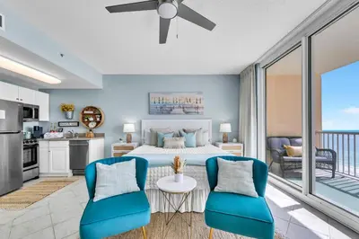 a bedroom with a bed and two blue chairs at Beachfront Studio #709 at Majestic in Panama City Beach