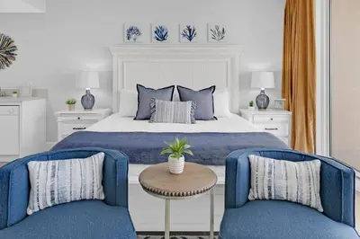 a bedroom with a bed and two blue chairs at Beachfront Studio #809 at Majestic in Panama City Beach