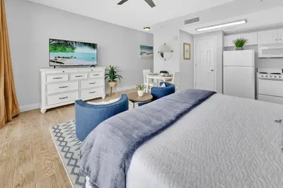 a bedroom with a large bed and a kitchen at Beachfront Studio #809 at Majestic in Panama City Beach
