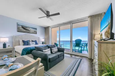 a bedroom with a bed and a living room at Beachfront Studio #909 at Majestic in Panama City Beach