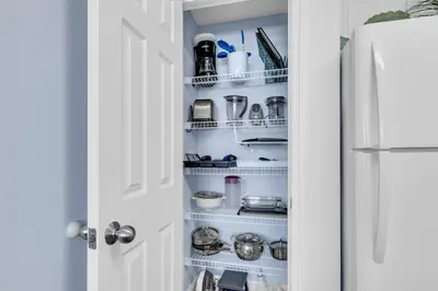 a kitchen pantry with white shelves and a refrigerator at Beachfront Studio #909 at Majestic in Panama City Beach