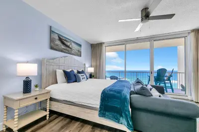 a bedroom with a bed and a couch and a window at Beachfront Studio #909 at Majestic in Panama City Beach