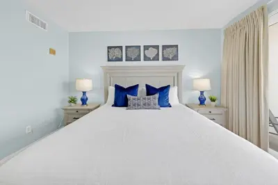 a bedroom with a large white bed with blue pillows at Gulfview Condo #1809 at Laketown Wharf in Panama City Beach