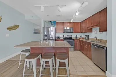 a kitchen with wooden cabinets and a island with bar stools at Gulfview Condo #1809 at Laketown Wharf in Panama City Beach