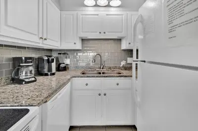 a white kitchen with a sink and a refrigerator at Oceanfront Condo #507 at Summit Beach Resort in Panama City Beach