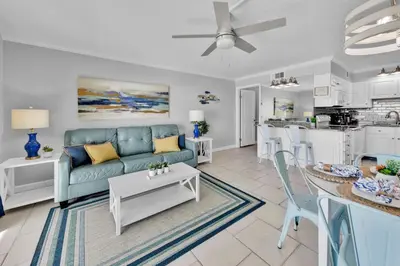 a living room with a blue couch and a kitchen at Oceanfront Condo #507 at Summit Beach Resort in Panama City Beach