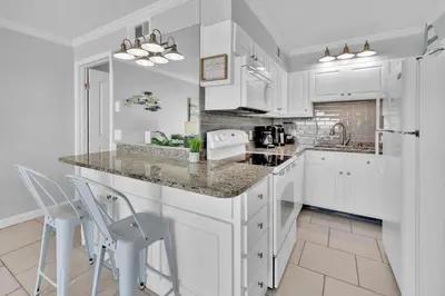 a kitchen with white cabinets and a counter and chairs at Oceanfront Condo #507 at Summit Beach Resort in Panama City Beach