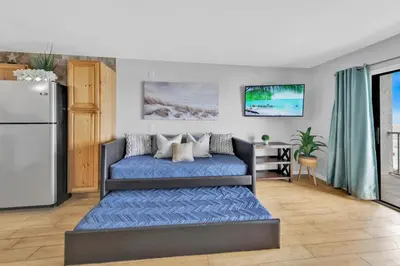 a living room with a bed and a refrigerator at Oceanfront Condo #629 at Summit Beach Resort in Panama City Beach