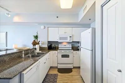 a kitchen with white cabinets and a white refrigerator at Shores of Panama # 1902 condo in Panama City Beach