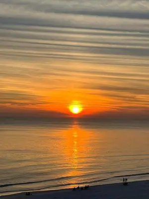 a sunset over the ocean with people on the beach at Shores of Panama # 1902 condo in Panama City Beach