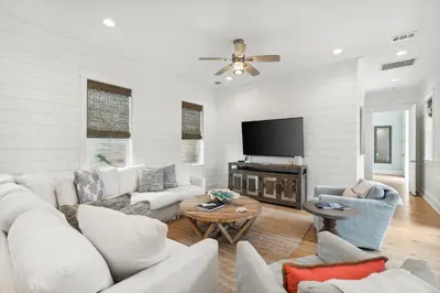 a living room with white furniture and a flat screen tv at 30A Beach House - Beach Please by Panhandle Getaways in Santa Rosa Beach