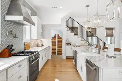 a kitchen with white counters and a staircase at 30A Beach House - Beach Please by Panhandle Getaways in Santa Rosa Beach