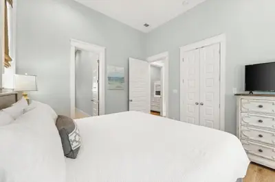 a white bedroom with a white bed and a tv at 30A Beach House - Beach Please by Panhandle Getaways in Santa Rosa Beach