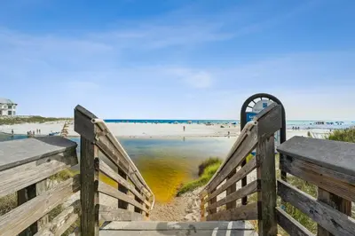a wooden staircase leading to a beach with a fence at 30A Beach House - Beach Please by Panhandle Getaways in Santa Rosa Beach