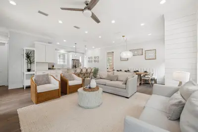 a living room with white furniture and a kitchen at 30A Beach House - Cozinest at Treetops by Panhandle Getaways in Rosemary Beach