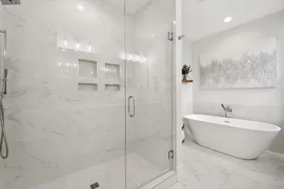 a white bathroom with a tub and a glass shower stall at 30A Beach House - Cozinest at Treetops by Panhandle Getaways in Rosemary Beach