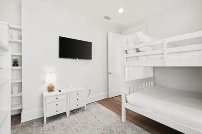 a white bedroom with a bunk bed and a tv at 30A Beach House - Cozinest at Treetops by Panhandle Getaways in Rosemary Beach