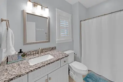 a bathroom with a sink and a toilet and a mirror at Sea Suite - Large hot tub with an easy walk to the beach in Santa Rosa Beach