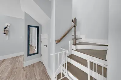 a staircase in a house with white walls and wooden floors at Sea Suite - Large hot tub with an easy walk to the beach in Santa Rosa Beach