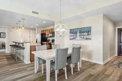 a dining room and kitchen with a white table and chairs at Origin at Seahaven #1703 by Nautical Properties in Panama City Beach