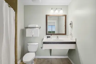a bathroom with a sink and a toilet and a mirror at Origin at Seahaven #1703 by Nautical Properties in Panama City Beach
