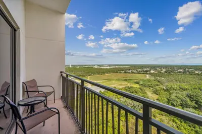a balcony with chairs and a view of a golf course at Origin at Seahaven #1703 by Nautical Properties in Panama City Beach
