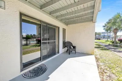 a patio with a chair and large sliding glass doors at Endless Summer E2 in Panama City Beach