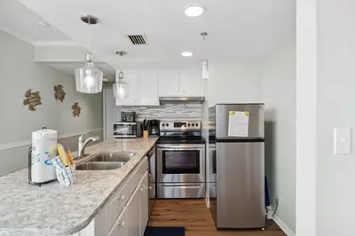 a kitchen with stainless steel appliances and white cabinets at Sunbird Resort! Incredible Beachfront Corner Unit! Free Beach Chairs! by Dolce Vita Getaways PCB in Panama City Beach