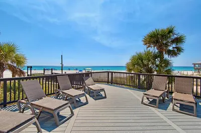 a wooden deck with chairs and the beach at Sunbird Resort! Incredible Beachfront Corner Unit! Free Beach Chairs! by Dolce Vita Getaways PCB in Panama City Beach