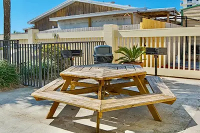 a wooden picnic table in front of a fence at Sunbird Resort! Incredible Beachfront Corner Unit! Free Beach Chairs! by Dolce Vita Getaways PCB in Panama City Beach