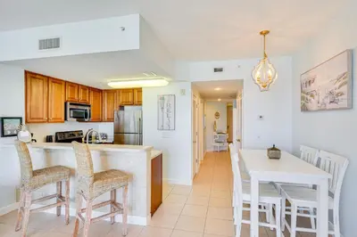 a kitchen with a counter and chairs and a table at Panama City Beach Paradise with Pool and Hot Tub! in Panama City Beach