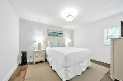 a white bedroom with a white bed and two lamps at Horizon South 11C1 in Panama City Beach