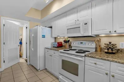 a kitchen with white cabinets and white appliances at Emerald Beach 930 in Panama City Beach