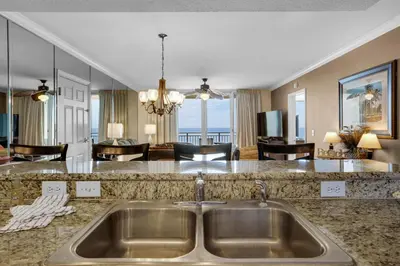 a kitchen with a sink and a living room at Emerald Beach 930 in Panama City Beach