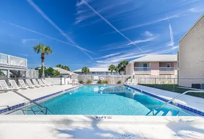 a swimming pool with chairs and a building at Southwind C-3 in Panama City Beach