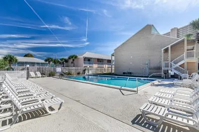 a swimming pool with lounge chairs next to a house at Southwind C-3 in Panama City Beach