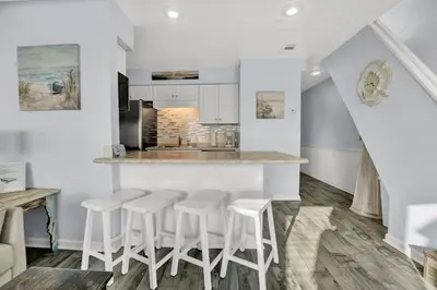 a kitchen with white counter stools and a counter top at Nautical Watch 14 B in Panama City Beach