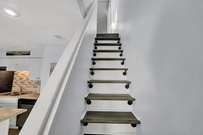 a staircase in a house with white walls and wooden steps at Nautical Watch 14 B in Panama City Beach